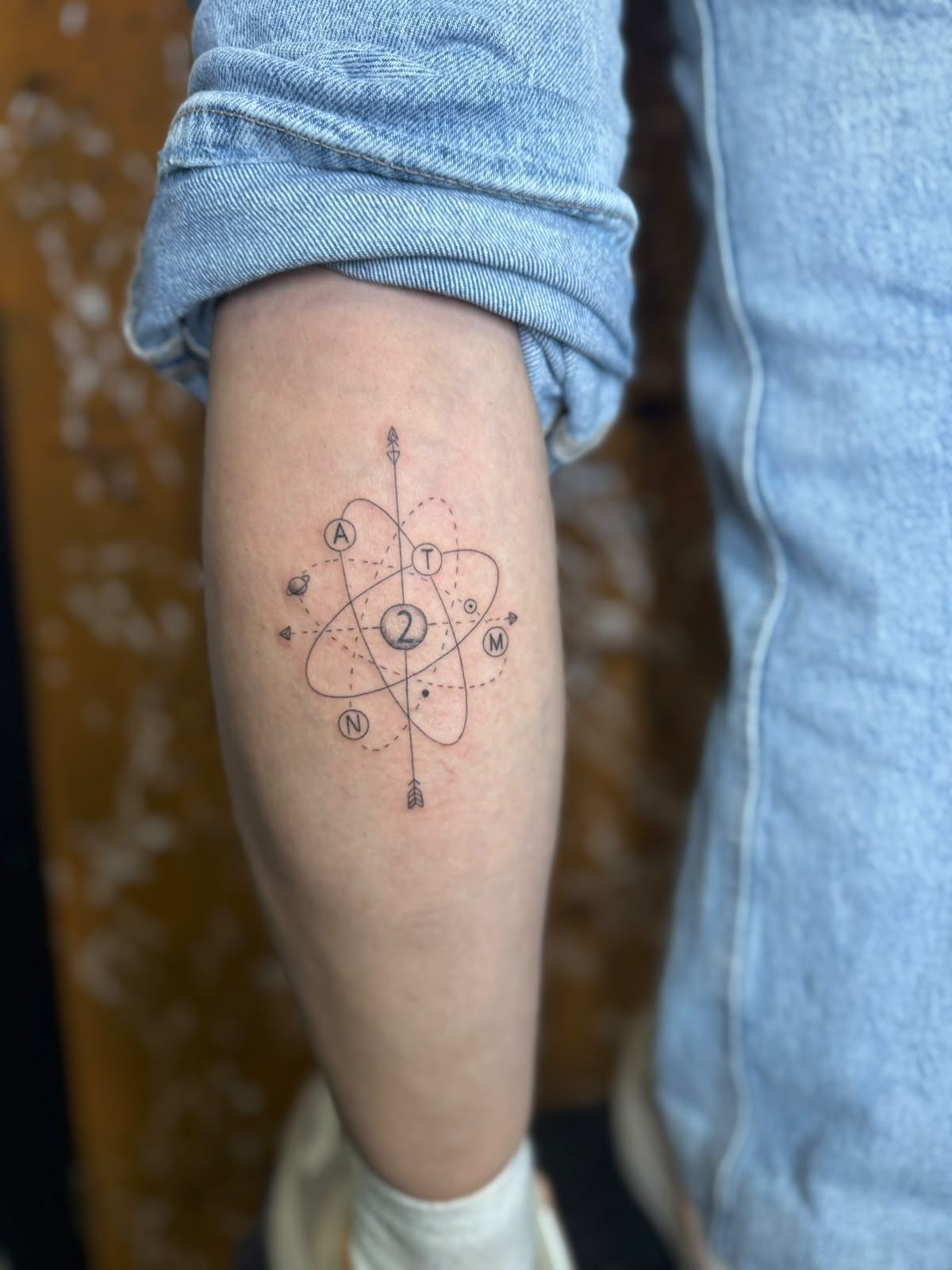 Tatuaje fine line geométrico de un átomo